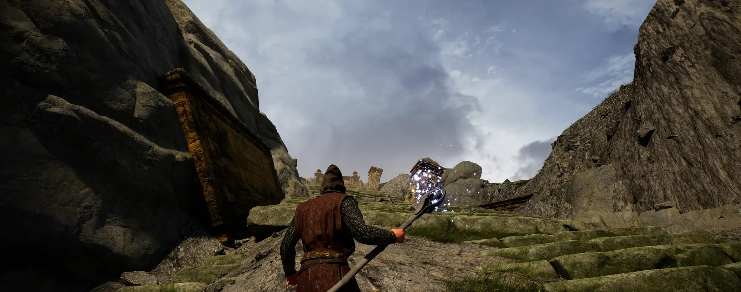 A hooded adventurer with a crystal-topped staff climbing a rocky mountain pass beneath a cloudy sky